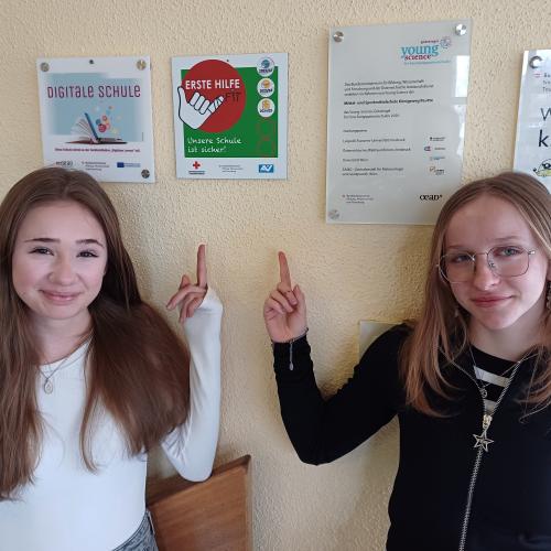 Schülerinnen zeigen auf die Plakette von Erste Hilfe Fit