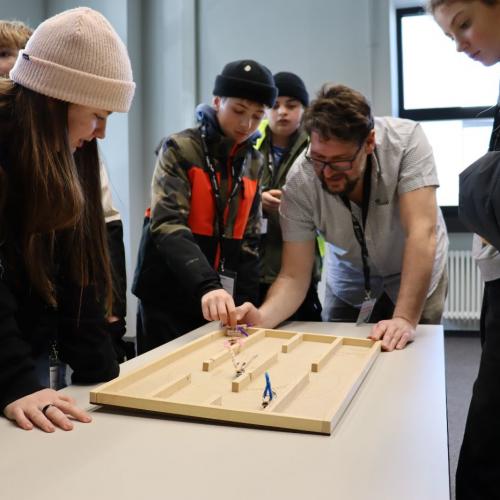 Mitarbeit zeigt den Schüler:innen ein Projekt.