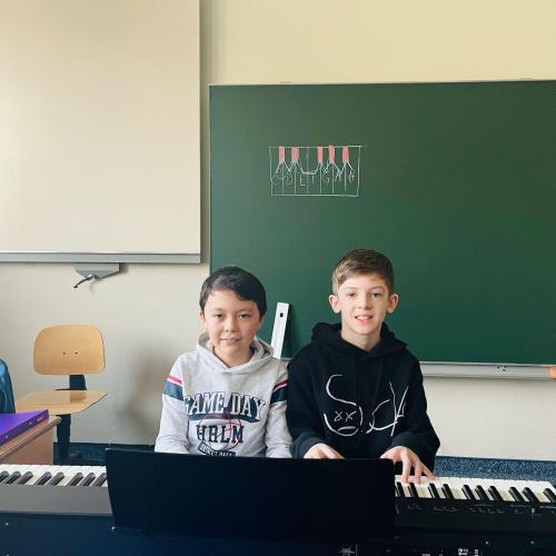 Zwei Schüler spielen am Klavier.