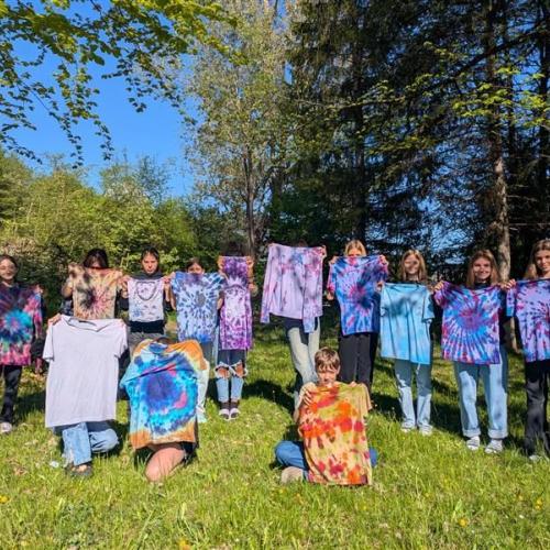 Schüler:innen zeigen ihre mit Batik gefärbten T-Shirts.