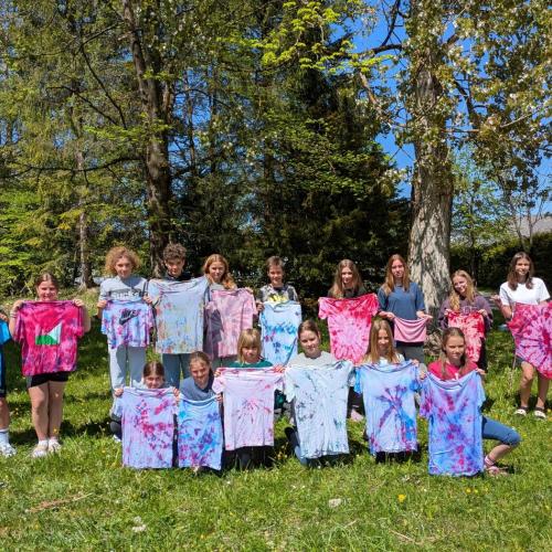 Schüler:innen zeigen ihre mit Batik gefärbten T-Shirts.