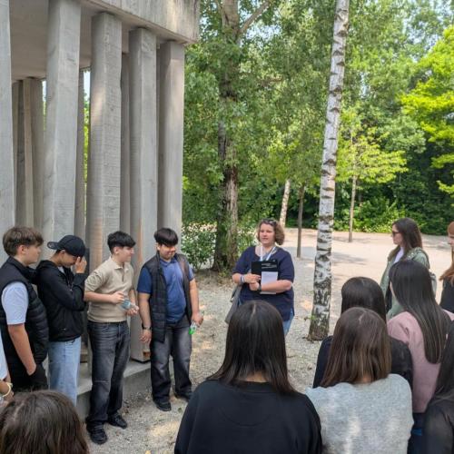 Schüler:innen hören der Führerin zu, die uns etwas über die Anfänge des KZ erzählt.