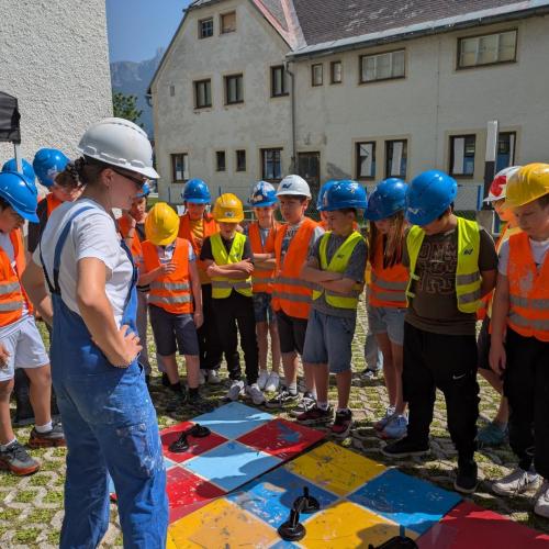 Baustellenleitung erklärt den Schüler:innen ihre Aufgabe Fenster einzusetzen.