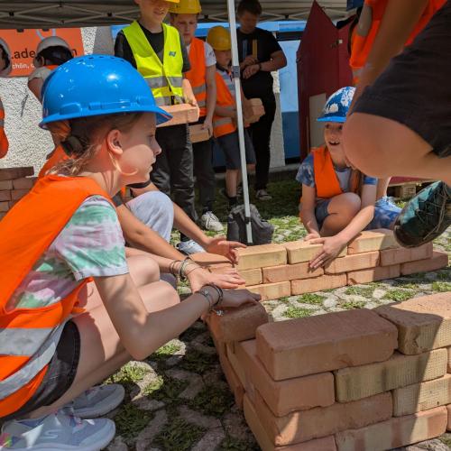 Schüler:innen bauen eine Wand aus Ziegeln.