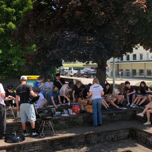 Schüler:innen im Pausenhof, sitzend, beim Essen.