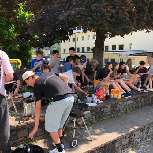 Schüler:innen im Pausenhof, sitzend, beim Essern.