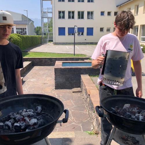 Grillfeier 4a im Pausehof. Zwei Schüler beim Grillen.