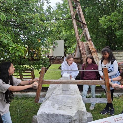 Museumsbesuch Laser Marmor. Schülerinnen versuchen einen Marmorblock zu zersägen.