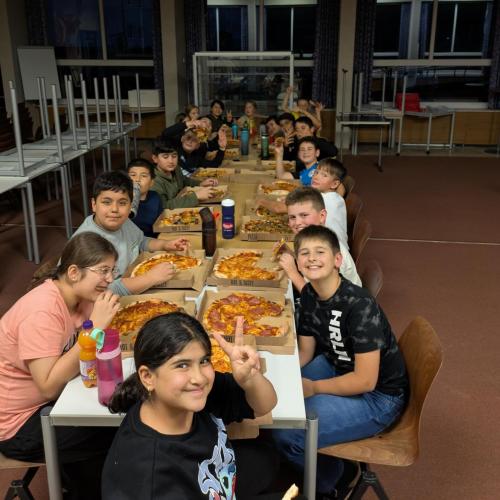Tischtafel in der Aula, die SuS der 1b essen Pizza.