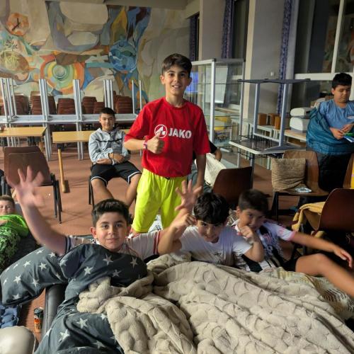 Die Schüler:innen machen es sich mit Polster und Decke in der Aula gemütlich, um einen Film anzusehen.