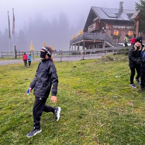Vertrauensspiel eine Schülerin hat die Augen verbunden und andere leiten sie mit Worten durch das Gelände.
