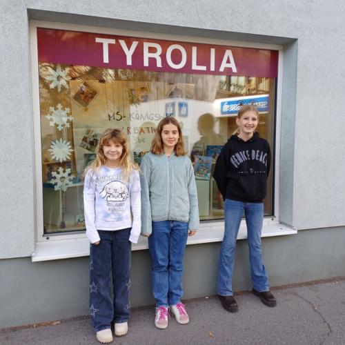 Schülerinnen stehen vor ihrem winterlich gestalteten Schaufenster der Tyrolia.