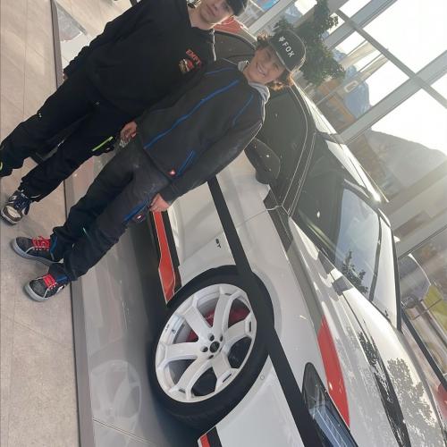 Zwei Schüler stehen vor einem Auto beim Autohaus Schweiger.