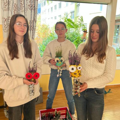 SchülerInnen, die ihre gestalteten Blumentöpfe in der Hand halten.