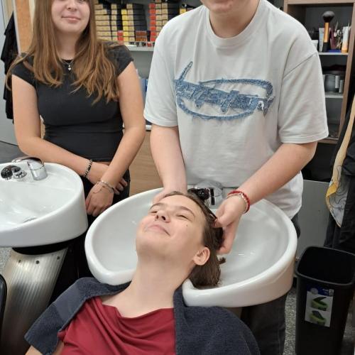 Schüler wäscht einer Mitschülerin die Haare.