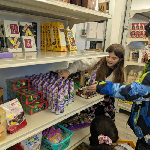Schülerinnen sortieren Waren im Paulusladen in die Regale. 