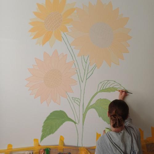 Schülerin beim Malen einer Blume in schönen Pastellfarben.