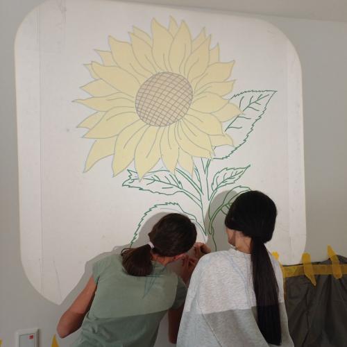Schülerinnen beim Malen der Blumen. Die Vorlage wird mit einem Overheadprojektor auf die Wand projiziert.