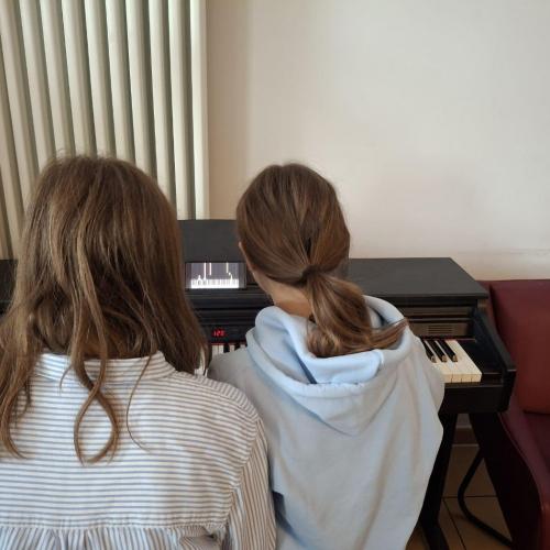 Schüler:innen sitzen an einem Piano.