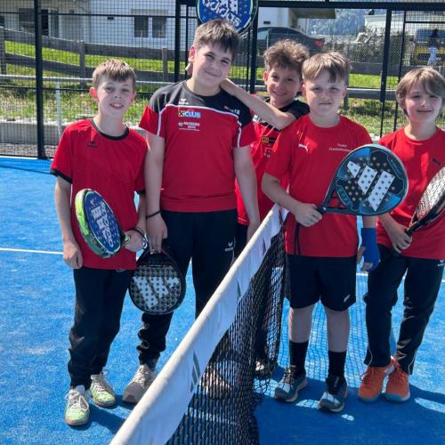 5 Schüler am Tennisnetz am Tennisplatz.
