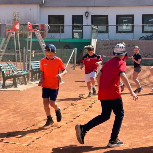 Schüler:innen beim Aufwärmen am Tenniscourt.