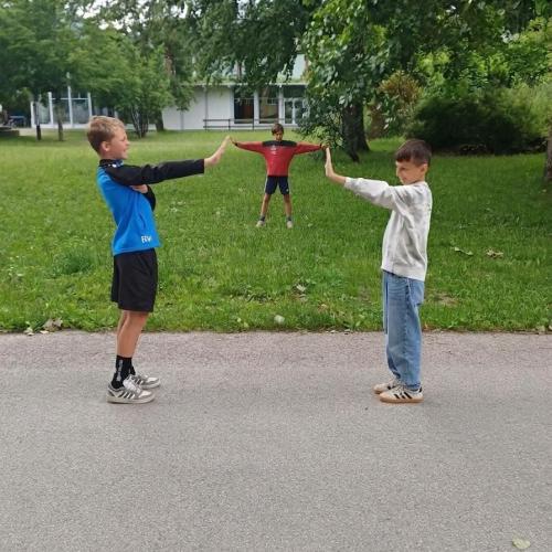 Es scheint, als würden zwei Schüler mit ihren Händen in der Mitte einen anderen Schüler, der kleiner erscheint, halten,