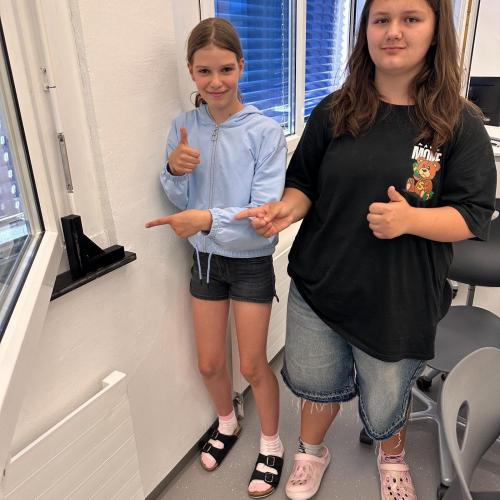 Schülerinnen präsentieren ihren 3D-gedruckten Fensterstopper.