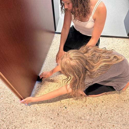 Schülerinnen schieben einen 3D-gedruckten Türstopper in eine Türe.