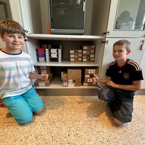 Schüler präsentieren die 3D Drucker Gegenstände im Kasten.