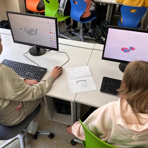 Zwei Schülerinnen sitzen vor dem PC und arbeiten mit dem 3D-Druck Programm.