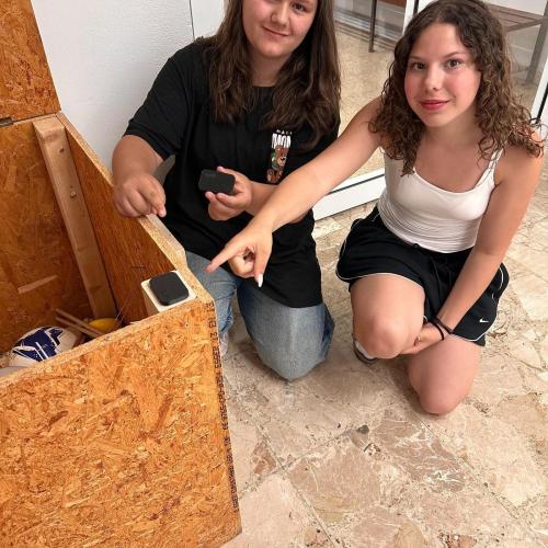 Schülerinnen präsentieren ihren 3D-gedruckten Schutz für unsere Sportpausenbox, damit der Deckel beim Schließen nicht direkt auf das Holz trifft.