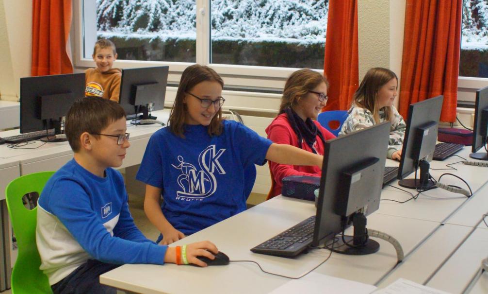 Eine Schülerin hilft einem Schüler am Computer