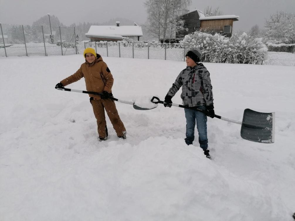 Zwei Schüler halten Schneeschaufeln in der Hand