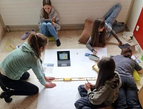 Schüler:innen arbeiten mit dem Tablet, Linealen an einem Projekt.