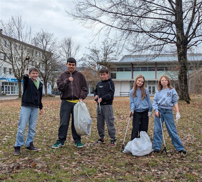 5 Schüler:innen beim Müll sammeln, um unsere Schulzentrum zu säubern.