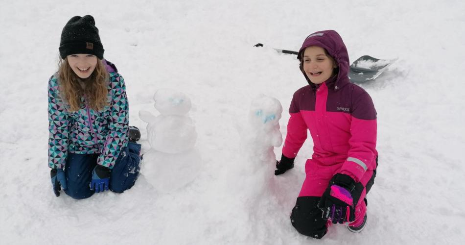 Zwei Schülerinnen präsentieren ihre Schneemänner