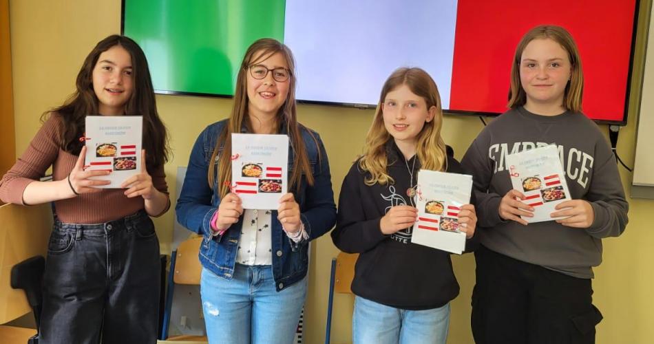 Schüler:innen der 1c zeigen ihr fertiges Kochbuch, dass alle Italienischschüler:innen gemeinsam gemacht haben.