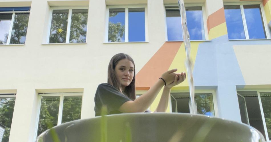 Das Wasser aus der Wasserflasche erscheint wie ein Wasserfall, in dem sich die Schülerin die Hände wascht.