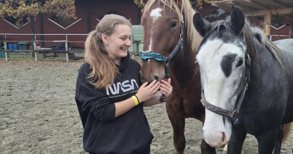 Eine Schülerin streichelt zwei Pferde.
