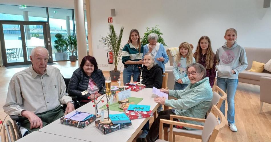Schüler:innen übergeben Bewohner:innen des Altersheims selbstgemachte Geschenke.