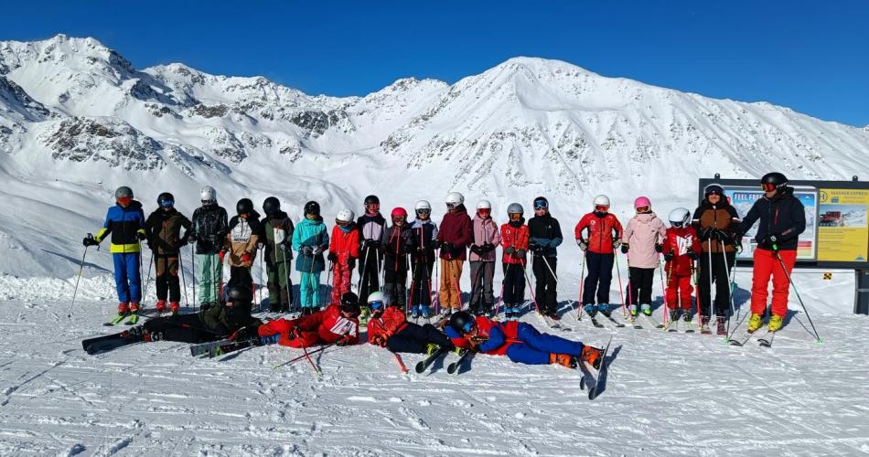 Gruppenfoto vor einer schneebedeckten Bergkulisse bei strahlendem Sonnenschein.