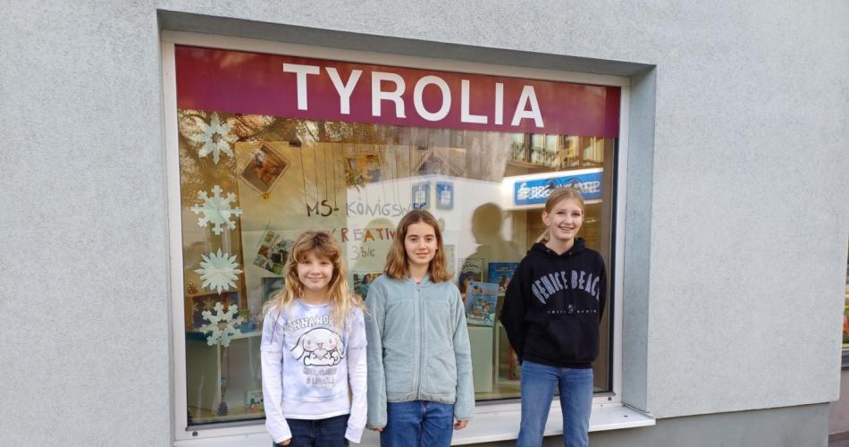 Schülerinnen stehen vor ihrem winterlich gestalteten Schaufenster der Tyrolia