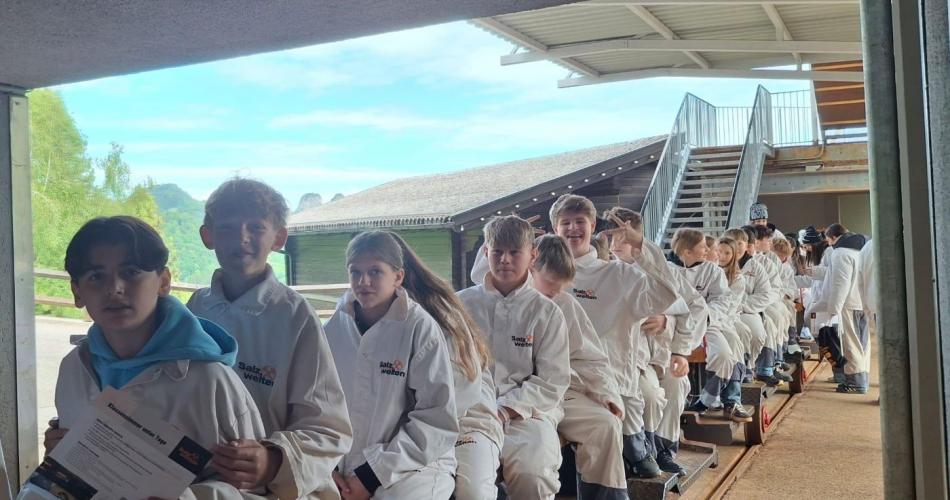 Salzbergwerk Salzburg. Schüler:innen sitzen auf dem "Zug", der sich ins Bergwerk bringt.