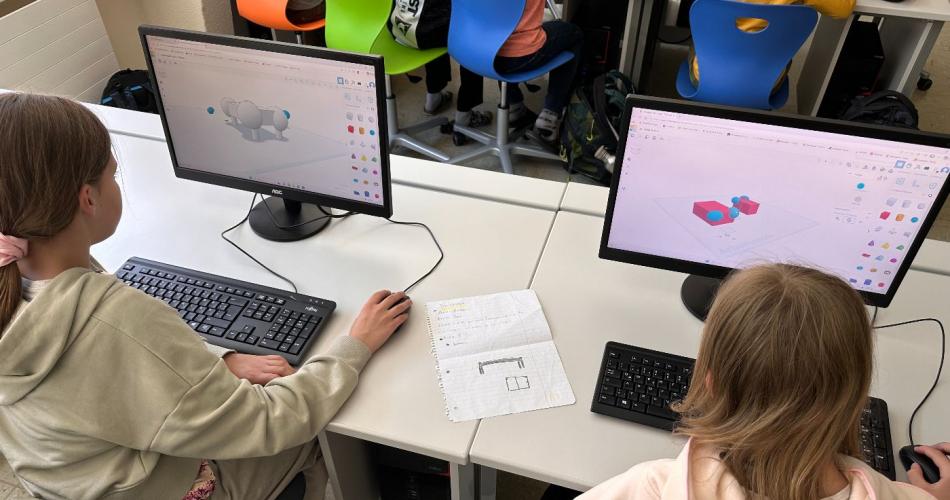 Zwei Schülerinnen sitzen vor dem PC und arbeiten mit dem 3D-Druck Programm.